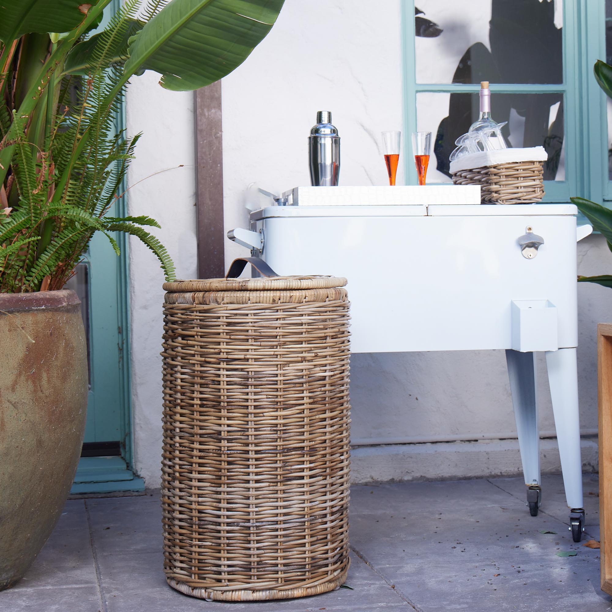 Tall Kubu Wicker Kitchen Trash Basket shown outside for entertaining | The Basket Lady
