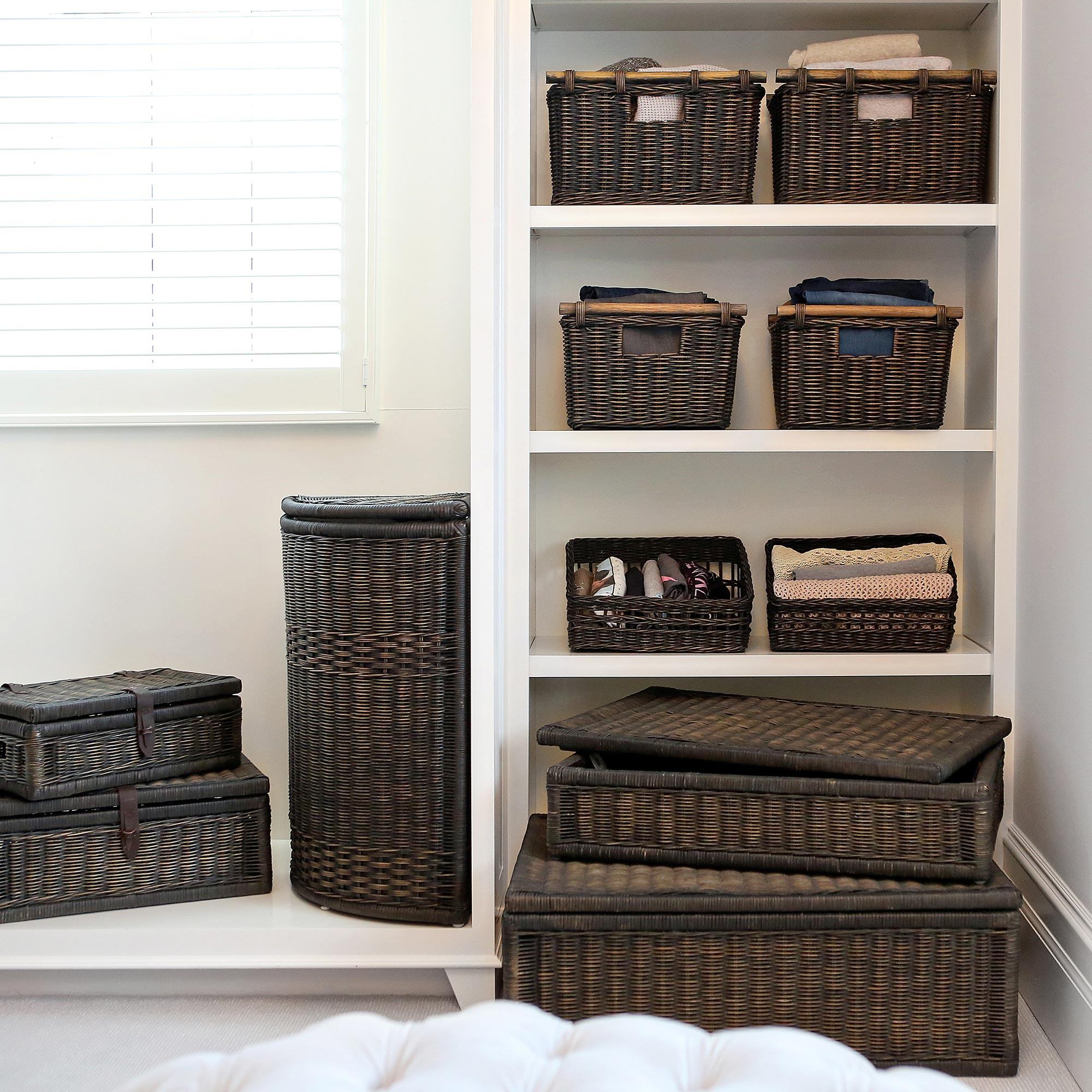 Walk-in closet with Antique Walnut Brown wicker storage baskets, lidded baskets, and corner laundry hamper